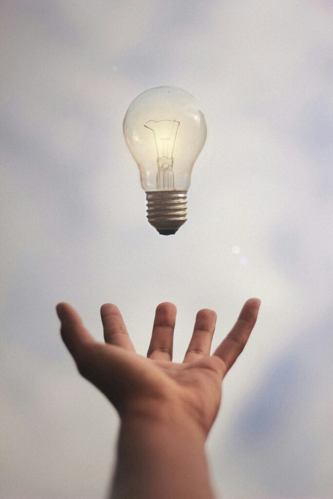 Floating lightbulb above a hand, symbolizing a question or idea