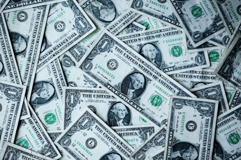 A pile of one dollar bills scattered randomly, representing the foundational potential of small earnings