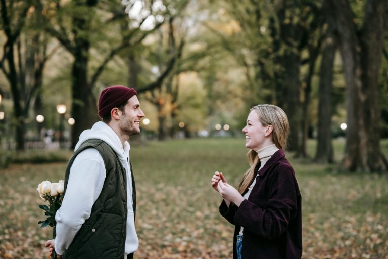 A young couple smiling and laughing together in a park during autumn, symbolizing the joy, excitement, and emotional connection felt during the honeymoon phase of a new relationship