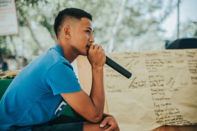 Young man holding a microphone, deep in thought before speaking, representing radical honesty and self-expression