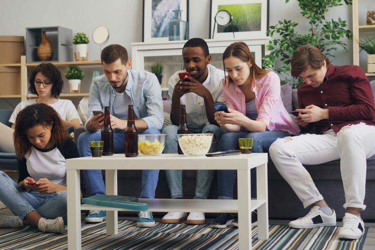 A group of friends silently using their smartphones, depicting the disconnected nature of social media despite physical proximity