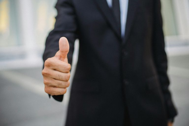 Businessman giving thumbs up symbolizing approval, recognition, and validation in the workplace