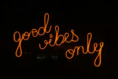 Orange neon sign reading "good vibes only" glowing against a dark background